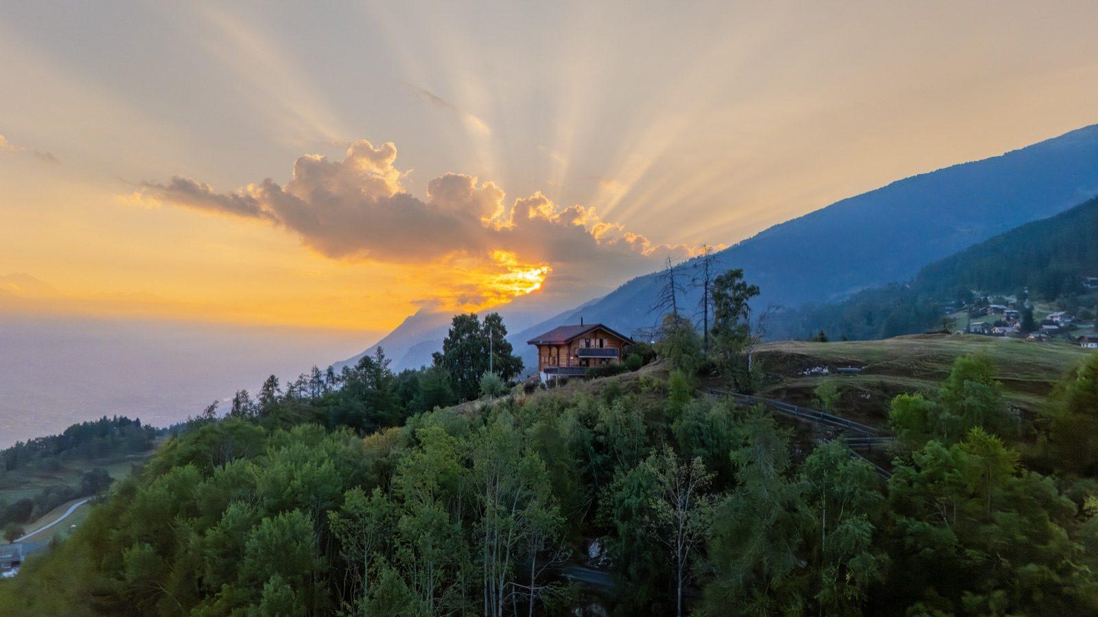 Chalet über dem Tal im Sonnenaufgang, aus der Luft aufgenommen